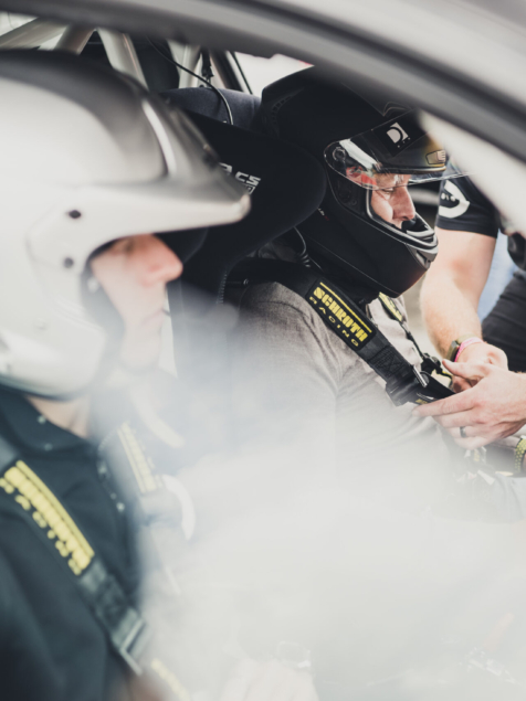 Racing drivers strapping into a car before a coaching session